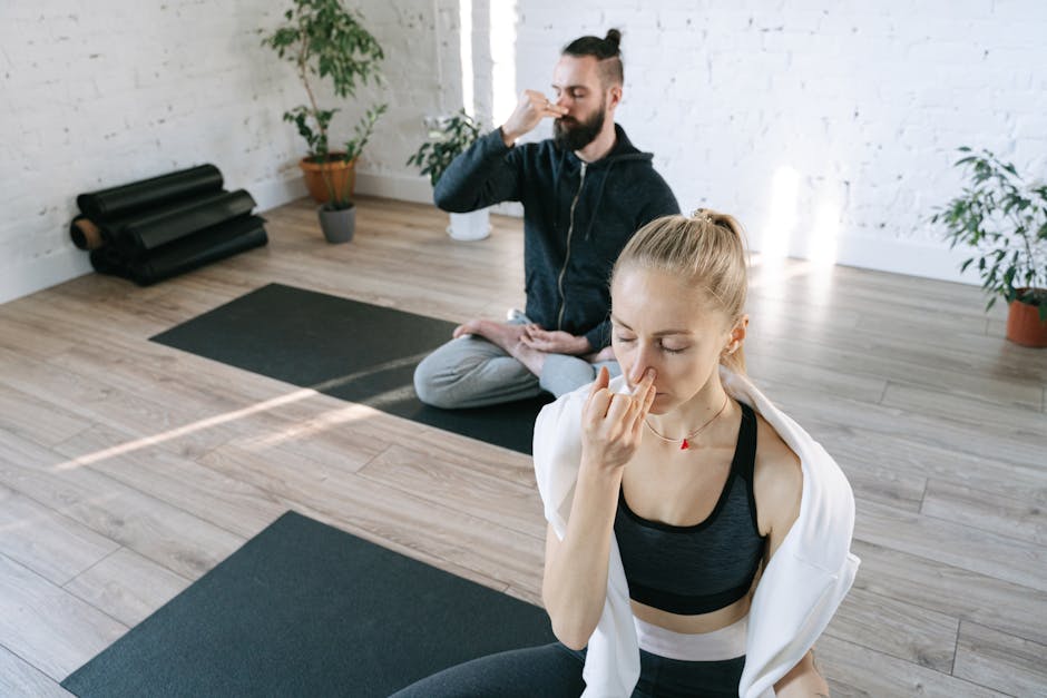 A man sits calmly with his eyes closed, practicing mindfulness in a sunlit room.